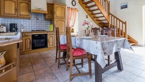 Una cocina con armarios de madera, una mesa de comedor con sillas y una escalera.