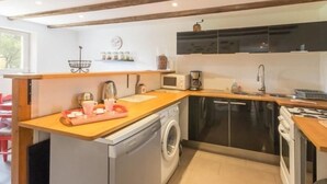 Une cuisine compacte équipée d’un lave-linge, d’un four à micro-ondes et d’une machine à café.
