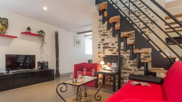 Un salon moderne avec un canapé rouge, un téléviseur et un escalier au design original.