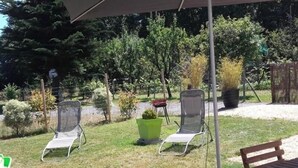 Un espace patio avec deux chaises de jardin et une table en bois, le tout installé sous un parasol.