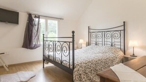 Une chambre à coucher avec un lit, des lampes de chevet, une fenêtre avec des rideaux et un plancher en bois.