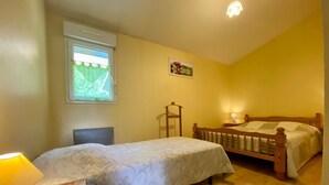 Een slaapkamer met twee bedden, een raam met uitzicht, een bedlampje en een houten stoel.