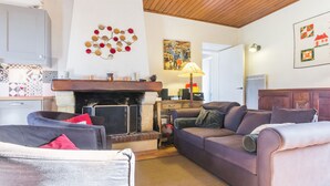 Ein gemütliches Wohnzimmer mit Kamin, einer Couch, einem Sessel und einem Essbereich mit Tisch und Stühlen.
