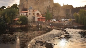 A historic castle with a church, a river, and a bridge. - Charming Renovated Cottage in Medieval Clisson with Terrace, Garden, and Modern Amenities (Clisson)