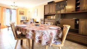 A dining area with a table set for four, surrounded by wooden chairs, a chandelier, and wooden cabinets with glass doors. - Charming Cottage with Garden near Nantes & Vannes – Pet-Friendly (La Chapelle-Launay)