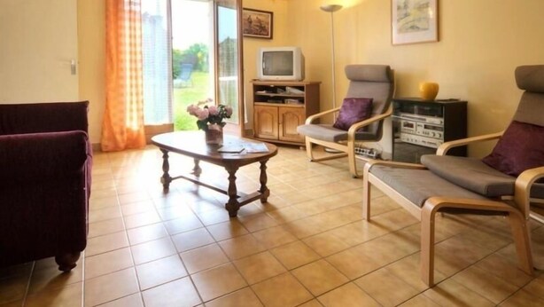 A living room with a sofa, armchairs, a coffee table, a television, and a cabinet. - Charming Cottage with Garden near Nantes & Vannes – Pet-Friendly (La Chapelle-Launay)