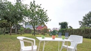 A white plastic table and chairs set in a grassy outdoor area with a hedge and trees in the background. - Charming Cottage with Garden near Nantes & Vannes – Pet-Friendly (La Chapelle-Launay)
