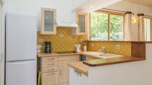Una cucina compatta con frigorifero, mobili in legno, lavandino e una finestra con tende.