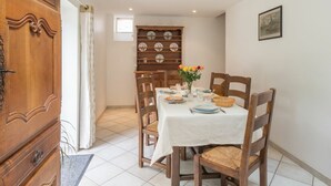 Una zona pranzo con un mobile in legno, un tavolo imbandito per quattro persone e una mensola a parete per piatti.