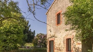 A rustic stone building with two windows and a door, surrounded by greenery and a dirt path. - Charming Cottage in Vineyards - Near Nantes & Clisson - WiFi, Family-Friendly (Monnières)