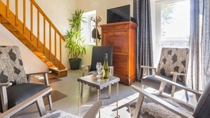 A living room with a staircase, a wooden cabinet, a potted plant, and two armchairs. - Charming Cottage in Vineyards - Near Nantes & Clisson - WiFi, Family-Friendly (Monnières)