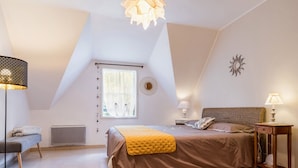 Een slaapkamer met een bed, nachtkastjes, een radiator, een raam met gordijnen en een plafondlamp.