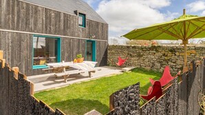 Un edificio rústico de madera con un muro de piedra y un patio con césped.
