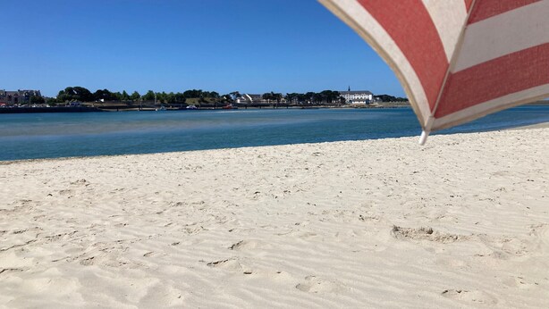 Una playa con vista despejada al agua y edificios al fondo.