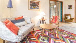 Una sala de estar con un sofá estampado, una alfombra colorida, una mesita y una silla.
