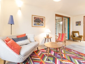 A living room with a patterned sofa, a colorful rug, a small table, and a chair. - Wooden House between Land and Sea in Guérande (Guérande)
