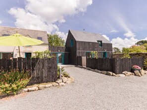 A modern house with a gravel driveway, a wooden fence, and a yellow umbrella. - Wooden House between Land and Sea in Guérande (Guérande)
