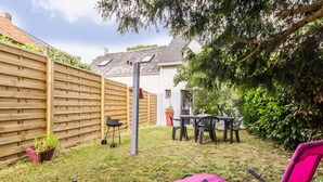 A backyard with a wooden fence, a table with chairs, and two pink lounge chairs. - "Charming Gîte in Brière Park, 15km from La Baule Beach" (Saint-Lyphard)