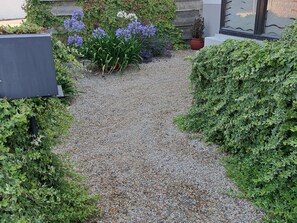 A gravel pathway flanked by lush greenery and flowering plants.