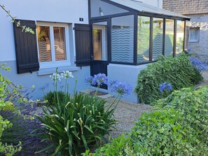 A house with a covered porch, a number '8' sign, and a garden with various plants and flowers.