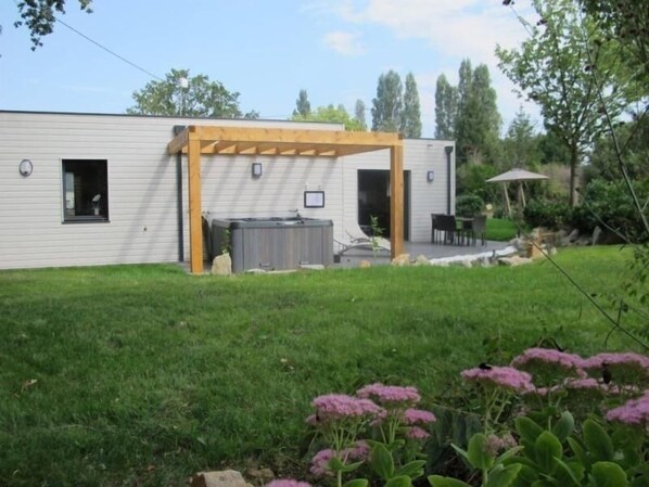 A modern house with a patio area, a hot tub, and a covered seating area.