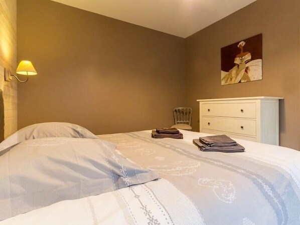 A bedroom with a bed, a nightstand, a lamp, a chair, and a dresser. - Cozy Wood Cottage with Spa, Garden, and Bikes - Near Nantes (Casson)