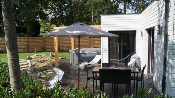A patio with a table and chairs, a covered seating area, and a hot tub. - Cozy Wood Cottage with Spa, Garden, and Bikes - Near Nantes (Casson)