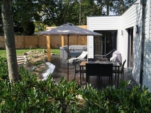 A patio with a table and chairs, a covered seating area, and a hot tub.