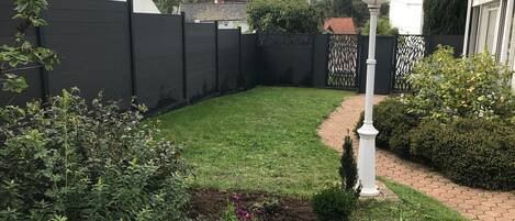 A well-maintained garden with a paved pathway, a white lamp post, and a variety of plants.