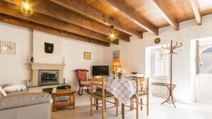 A cozy living room with a fireplace, a dining table with chairs, a sofa, and a TV.