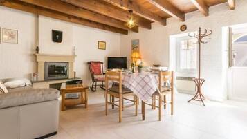Un salon confortable avec une cheminée, une table à manger avec des chaises, un canapé et un téléviseur.