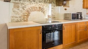 A kitchen with wooden cabinets, a built-in oven, a microwave, and a stone backsplash.
