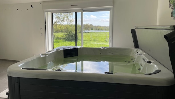 A modern bathroom with a large window, a bathtub, and a shower area.