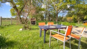 An outdoor dining area with a round table and four orange chairs, surrounded by greenery and trees. - Renovated mill with enclosed garden near Pornic (Pornic-Le Clion sur Mer)