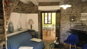 A cozy room with a bed, a small table, and a chair. There is a dining area visible through an open door. - Renovated mill with enclosed garden near Pornic (Pornic-Le Clion sur Mer)