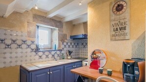 Una cocina con salpicadero de azulejos, encimera de madera y un reloj en la pared.
