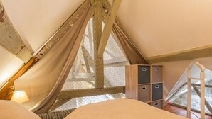 Un dormitorio abrigado en el desván, con cama, escalera y un espacio de almacenamiento.