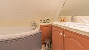 Un baño con una bañera independiente, un lavamanos y armarios de madera.