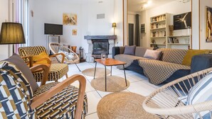 A modern living room with a fireplace, comfortable seating, and a bookshelf. - Spacious Ground-Level Home with Large Yard, Terrace, WiFi, and Game Amenities in Malville (Malville)