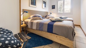 A bedroom with a wooden bed, two bedside tables, a blue rug, and a window with a view of trees. - Spacious Ground-Level Home with Large Yard, Terrace, WiFi, and Game Amenities in Malville (Malville)