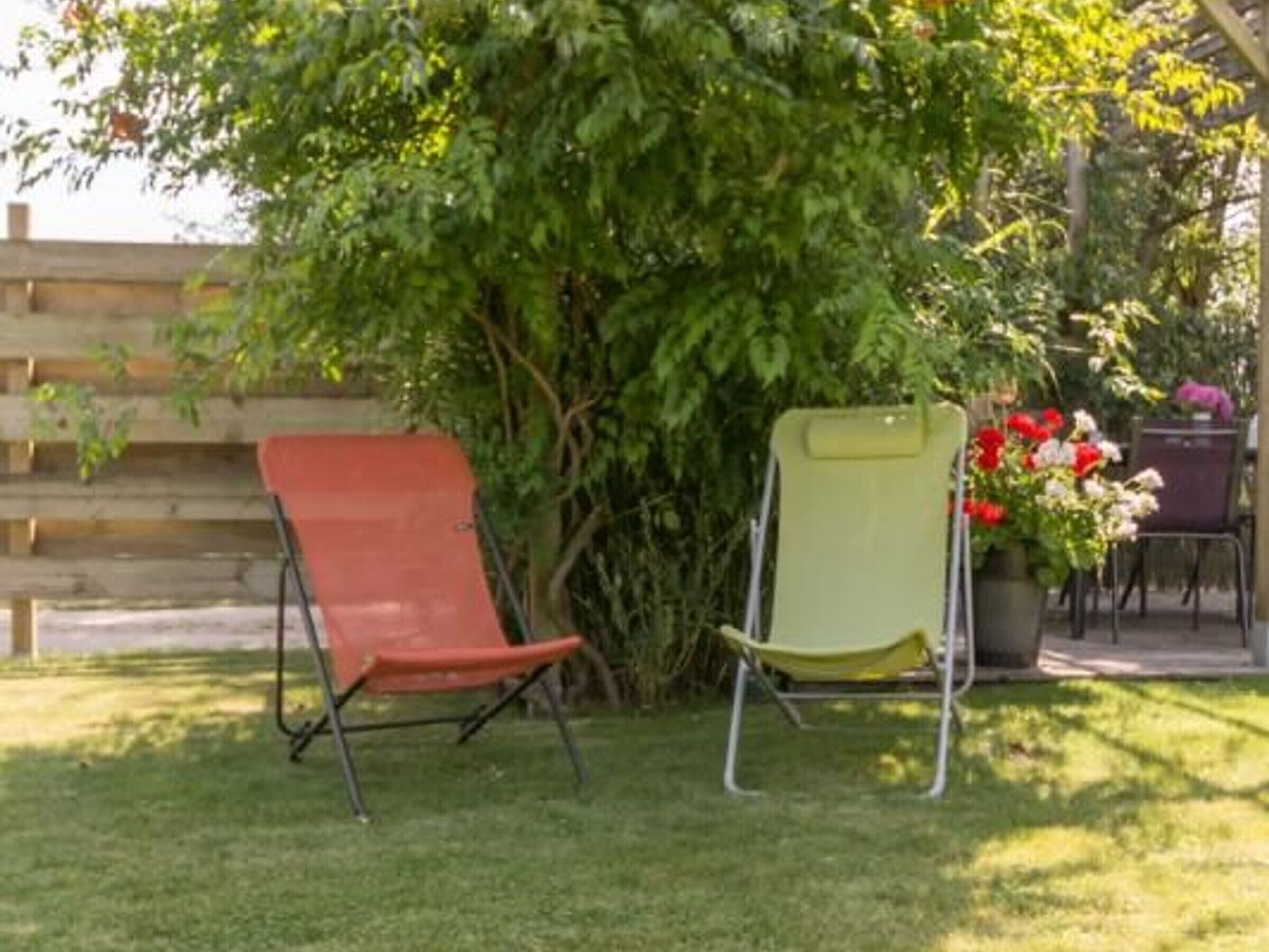 A garden with two lawn chairs and a potted plant with flowers.