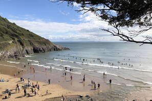 Una spiaggia con persone che fanno surf e passeggiano sulla riva.