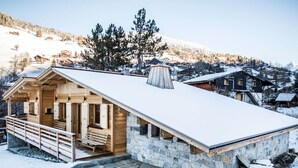 Uma cabana de madeira com base de pedra, varanda e telhado coberto de neve.