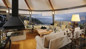 A spacious living area with a fireplace, comfortable seating, and large windows offering a view of the landscape. - Luxury Villa Bahía with Infinity Pool, Panorama View, Sauna & Fitness Area (El Sauzal)