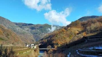 A river valley with a bridge, snow-covered fields, and a mountain backdrop.