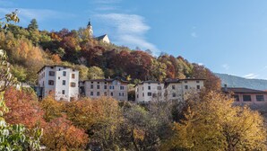 A hillside with buildings, including a church, surrounded by autumn foliage. - Holiday Apartment "Casa di Ada" with Mountain Views and Wi-Fi (Segonzano)