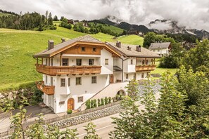 En toetages chalet med balkon, sten trapper og udsigt over de omkringliggende bakker.
