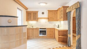 A kitchen with wooden cabinets, a tiled floor, and a built-in oven. - Holiday Apartment "Désirée Dolasilla" with Balcony, Mountain View, Wi-Fi & TV (St. Vigil)