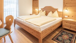 Een houten bed met hoofdeinde, nachtkastjes, een stoel en een vloerkleed.