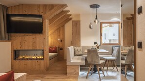 Un interior modern amb una llar de foc, parets de fusta, una zona de menjador i un televisor fixat a la paret.